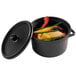 A Solia black plastic mini pot with a lid containing soup and vegetables.