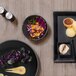 A table with black Front of the House Spiral Ink bowls filled with food.