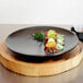 A Front of the House semi-matte black porcelain plate with food on it.