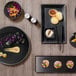 A table with Front of the House Spiral Ink black porcelain plates filled with food.