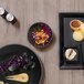 A table set with black porcelain ramekins filled with food.