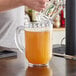 A man pouring a drink into a Carlisle clear plastic pitcher.