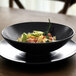 A Front of the House Semi-Matte Black Porcelain Wide Bowl with pasta and vegetables inside.