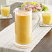 A Carlisle clear polycarbonate pitcher of orange juice on a table.