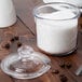 A Cambro Camwear condiment jar with sugar on a table.