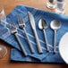 Acopa Phoenix flatware on a blue napkin.