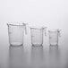 A group of three clear plastic measuring cups with purple writing.