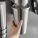 A hand holding a silver AvaMix stainless steel malt cup.