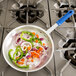 A Vollrath Wear-Ever fry pan filled with chopped onions and peppers on a stove.