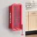 A red Cato fire extinguisher box mounted on a wall with a hammer attachment.