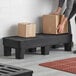 A man using a black Regency Dunnage Rack with slotted top to hold boxes.