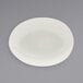 A white semi-matte scallop oval porcelain bowl on a gray surface.