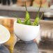 A white bowl filled with green peppers on a table.