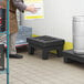 A man using a black plastic Regency dunnage rack with a slotted top.