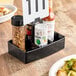 A black Carlisle condiment caddy with a white sign on it.