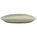 A close-up of a Front of the House Tides porcelain oval plate with a curved edge.