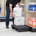 A man using a Regency black plastic display base to stack boxes on a shelf.