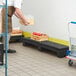 A man holding a black Regency plastic dunnage rack with boxes of food on it.