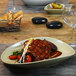 A Front of the House Tides porcelain oval platter with food on a table.