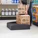 A man holding a stack of boxes on a black plastic Regency spot merchandiser.