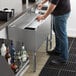 A man sliding a bottle into a Regency underbar ice bin filled with ice.