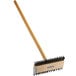 A Carlisle Sparta Broiler Master grill brush with a wooden handle and metal bristles.