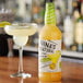 A bottle of Nina's Natural Ultimate Margarita Mix next to a glass of margarita with lime.