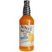 A bottle of Nina's Natural mango puree mix with orange liquid inside.