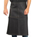 A man wearing a black denim Uptown Bistro apron with black webbing.