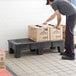 A man placing a box on a black plastic Regency dunnage rack.