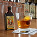 A glass of King Floyd's Barrel Aged Aromatic Bitters next to a glass of brown liquid with an orange slice.