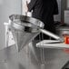 A woman using a Choice coarse China cap strainer and wire mesh stand.