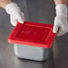 a person wearing gloves holding a red tray