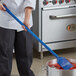 A person using a Carlisle blue paddle with a nylon blade and polypropylene handle to stir food in a pot.