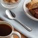 An Acopa Lydia stainless steel demitasse spoon in a cup of coffee on a table.