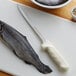 A Dexter-Russell Sani-Safe fillet knife cutting a fish on a cutting board.