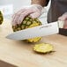 A person using a Dexter-Russell Sani-Safe Chef Knife to cut a pineapple