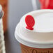 A Royal Paper Stix To Go red beverage plug and stirrer in a coffee cup with a lid.