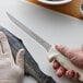 A person using a Dexter-Russell Sani-Safe Flexible Fillet Knife to cut a fish.