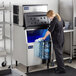 A woman in a black shirt pouring water into an Avantco Ice air cooled ice machine.