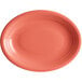 An Acopa Capri coral oval stoneware coupe platter with a white background and a bright orange rim.