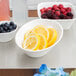 A tray with bowls of raspberries, blackberries, blueberries, and lemon slices on a counter.