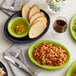 An Acopa Capri deep sea cobalt stoneware coupe platter on a table with plates of food and glasses of red wine.