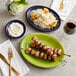 An Acopa Capri deep sea cobalt oval stoneware platter with rice and chicken on a table.