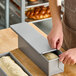 A rectangular glazed aluminized steel sliding cover being placed on a Pullman bread pan.