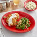 An Acopa Capri oval stoneware platter with fried chicken and a side salad on a table.