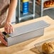 A rectangular glazed aluminized steel sliding cover designed for a 16 inch by 4 inch Pullman bread pan.