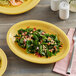 An Acopa Citrus Yellow oval stoneware platter with food on it.