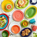 A stack of green and yellow Acopa Capri stoneware plates on a table with a grapefruit slice on one plate.