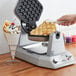 A person putting a bubble waffle in a Waring commercial waffle maker.